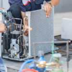 Two male workers in uniform doing air conditioner repair