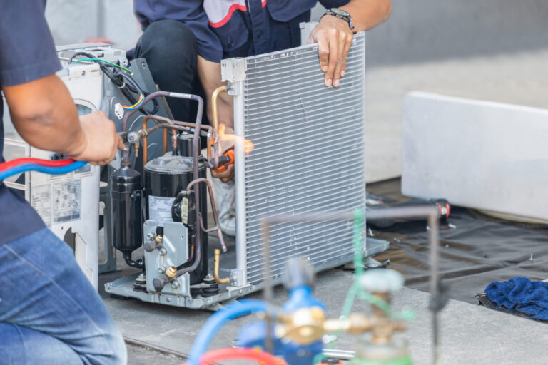 Two male workers in uniform doing air conditioner repair